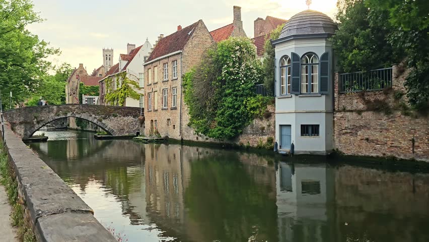 Beautiful medieval buildings lining the canals of Bruges, Belgium at sunset. Handheld walking motion.