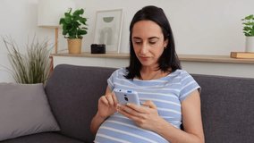 Young pregnant woman using smartphone on sofa - Powered by Shutterstock - Get 15% off with code: PIKWIZARD15