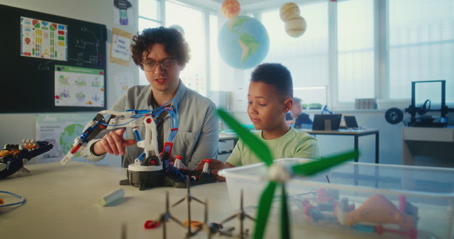 Science and Technology Lesson: Elementary School Student Studying Model of Robotic Arm. Young Teacher Educating Smart African American Boy in Modern Classroom. Interactive Learning and STEM Education.