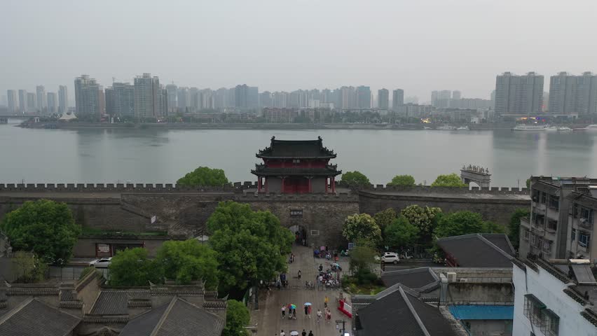 Aerial view of xiangyang city wall and linhan gate during the daytime with people walking and activity near the water