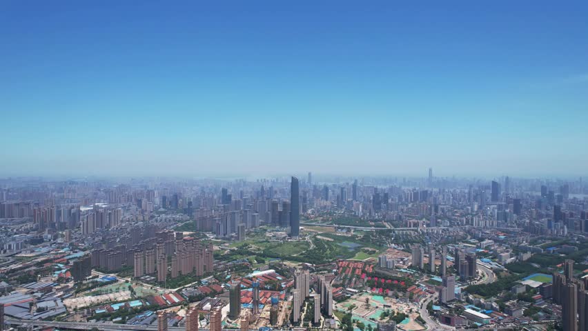 Aerial pan of Zhengzhou City showing dense cityscape and landmark buildings on a sunny day in Henan Province, China