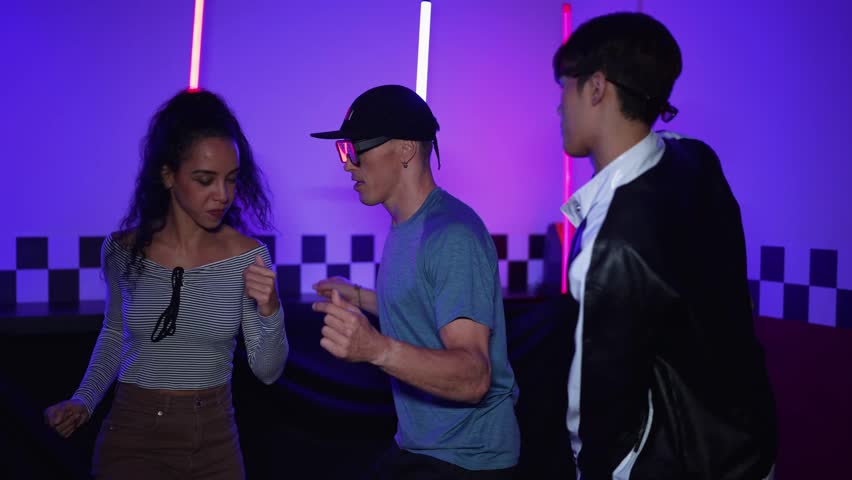 Multicultural break dancing team moving to music at studio with purple neon light. Energetic street dancer group dancing freestyle movement while looking diverse friend at studio. Crazy. Regalement.