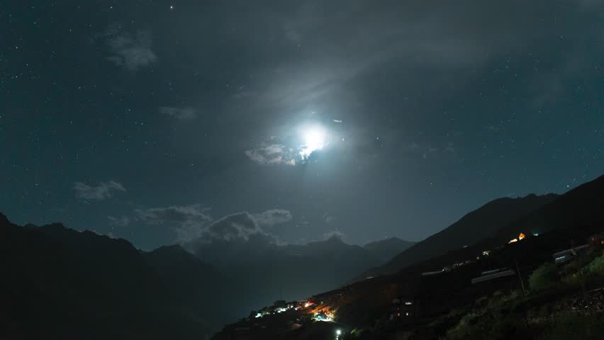 4K Night lapse of Moonset over mountains at Gondhla village in Lahaul Valley, Himachal Pradesh, India. Nightlapse of clouds and moon moving in sky during night. Nature background. Travel to new places