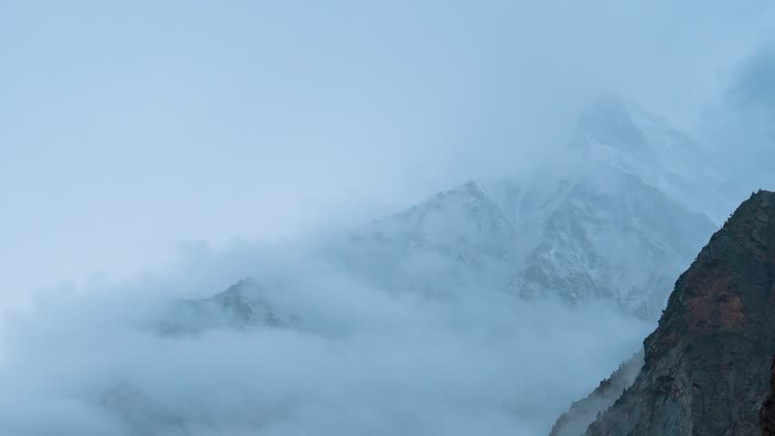 4K Time Lapse of dark monsoon clouds rolling in snowy Himalaya mountains at Miyar Valley, Lahaul, India. Snow storm, bad weather, stormy clouds in mountains. Snow storm during winter in Himalayas