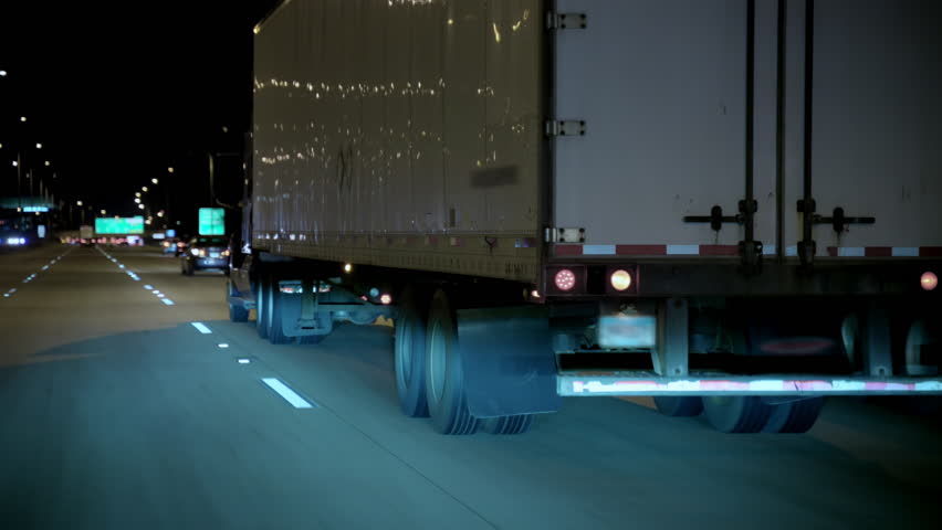 Driving close to the white truck trailer on the highway at night time. Wide POV wide shot shot