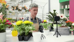 A man is recording a gardening video with plants and flowers in a greenhouse. - Powered by Shutterstock - Get 15% off with code: PIKWIZARD15