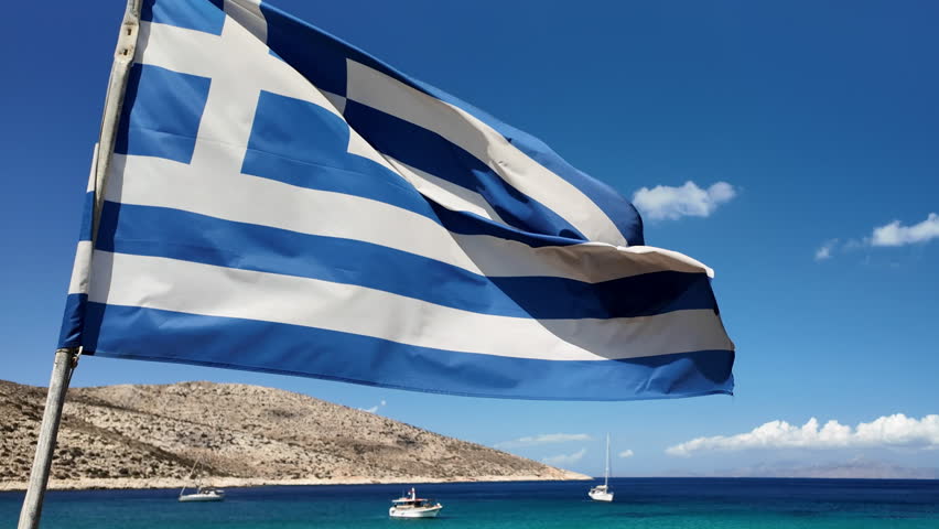 View of a huge greek national flag at the turquoise dream beach of Agia Theodoti in Ios Greece in slow motion