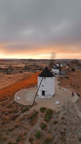 Aerial view of the historic windmills of Consuegra at sunset, Castilla-La Mancha, Spain. Old historic windmills of Don Quixote character on the hills in evening light. Molinos de Viento de Consuegra