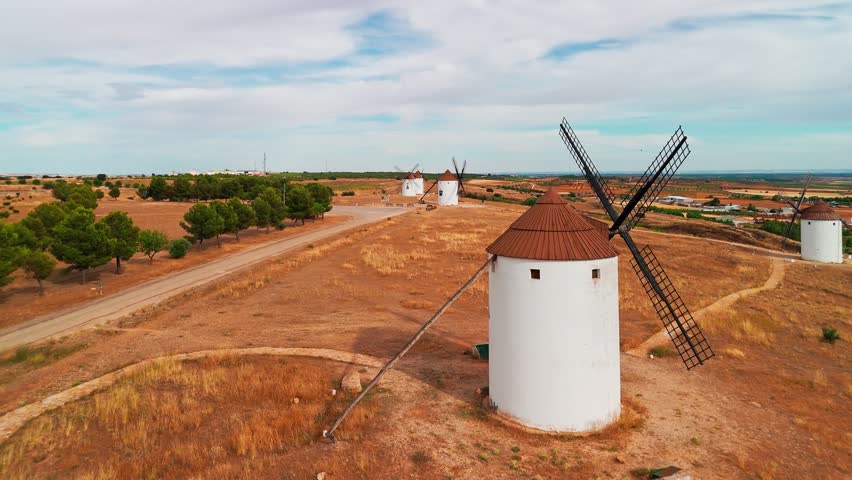 Aerial view of the historic windmills of Mota del Cuervo, Castilla-La Mancha, Spain. Old historic windmills of Don Quixote character on the hills in evening light. Molinos de Viento de Mota del Cuervo