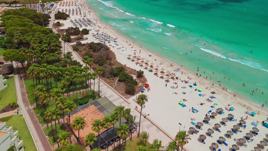 Aerial view of Platja de sa Coma beach in Mallorca, Balearic Islands, Spain. Stunning white sand beach with turquoise waters, surrounded by a beautiful resort on Majorca island during summer.