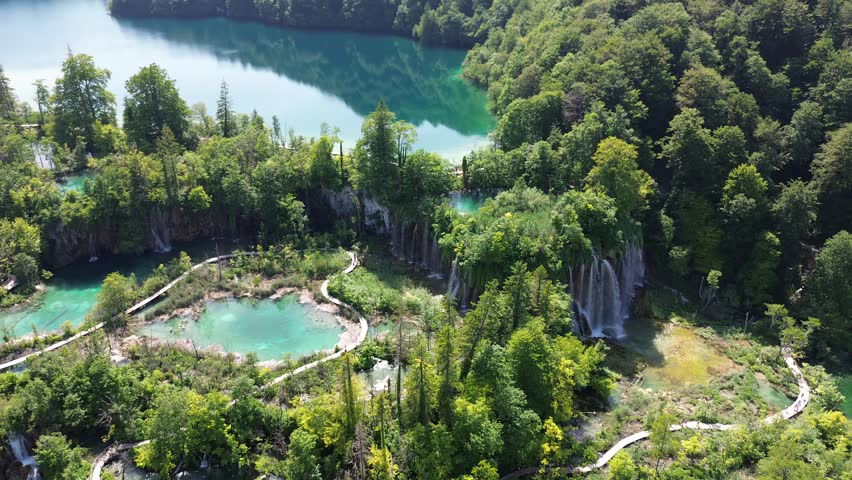 High-altitude aerial of Plitvice Lakes National Park. Stunning top-down view of water channels cutting through green wilderness.