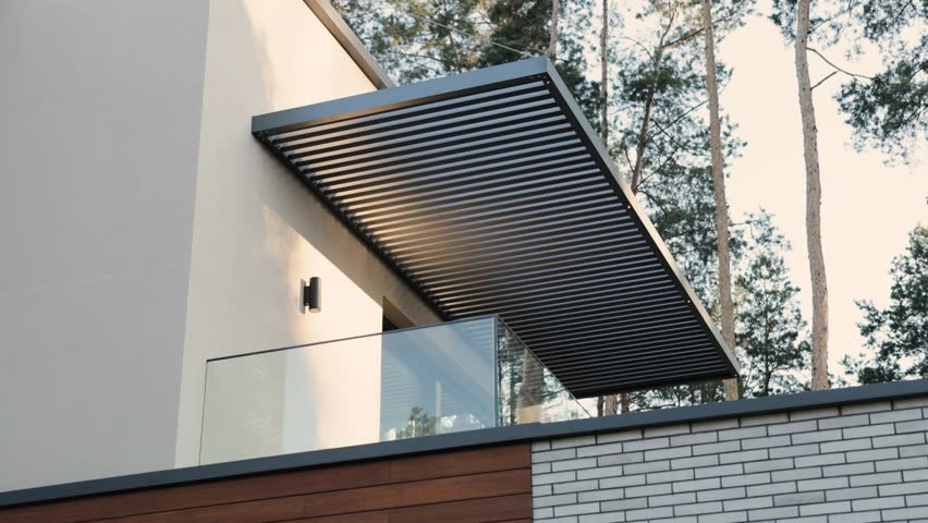 Modern balcony design in a private two-story house overlooking a forest landscape. A stylish balcony with a modern pergola is surrounded by lush trees, creating an inviting outdoor space.