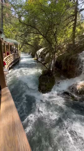 View of mountain river with crystal clear water among mossy stones and scenic fall woods in Jiuzhaigou nature reserve (Jiuzhai Valley National Park), China.