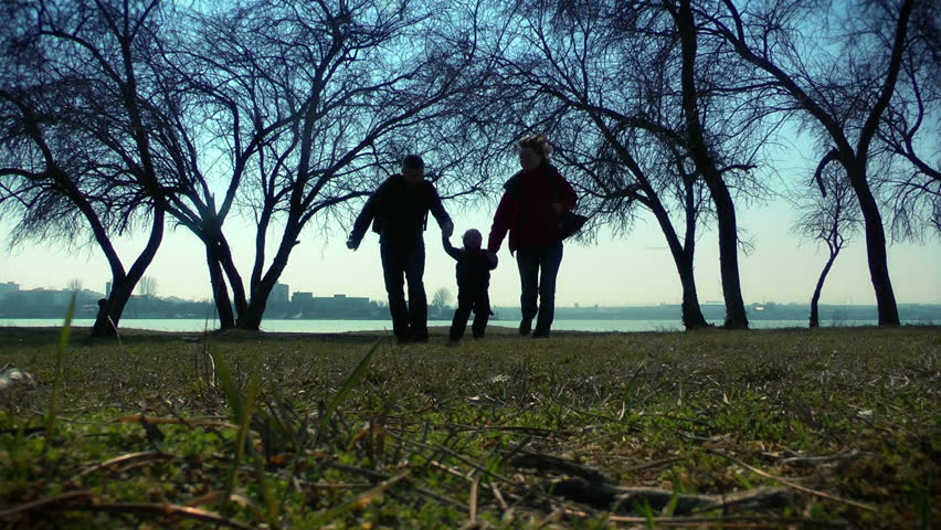 Happy couple with little boy running in the park. silhouettes