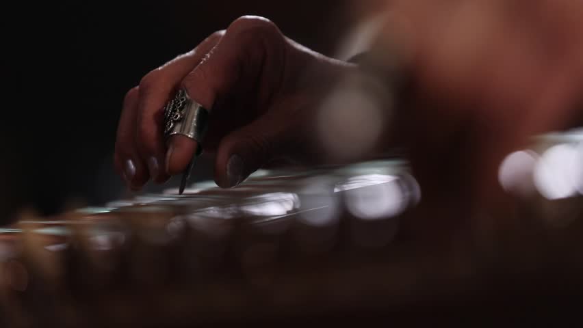 close-up shows a woman's hands playing an ornate wooden zither with plectrums. A microphone captures the beautiful sound of this traditional Middle Eastern folk instrument.
