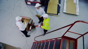 A mature male warehouse manager or foreman descends a flight of stairs to talk to one male and one female member of his staff. High angle view. - Powered by Shutterstock - Get 15% off with code: PIKWIZARD15