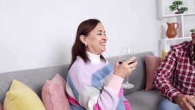 Elderly couple enjoying a glass of wine together on their comfortable sofa, sharing moments of joy and relaxation at home - Powered by Shutterstock - Get 15% off with code: PIKWIZARD15