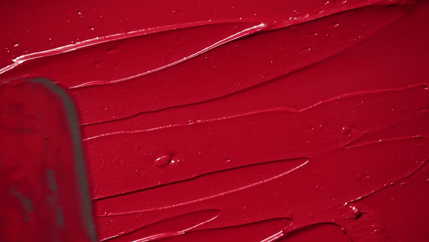 Red lipstick texture smeared in smooth, creamy strokes. Bold cosmetic background perfect for beauty, fashion, and makeup related themes. Red lipstick background.