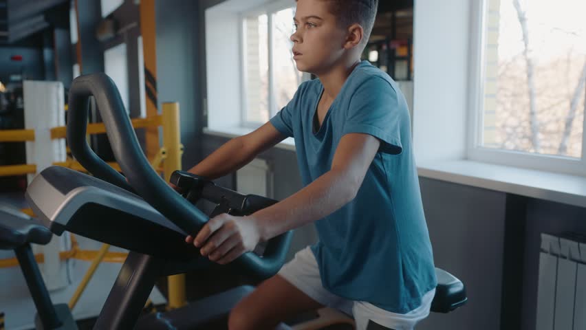 Teenage boy enjoying physical exercise training on mechanical elliptical trainer
