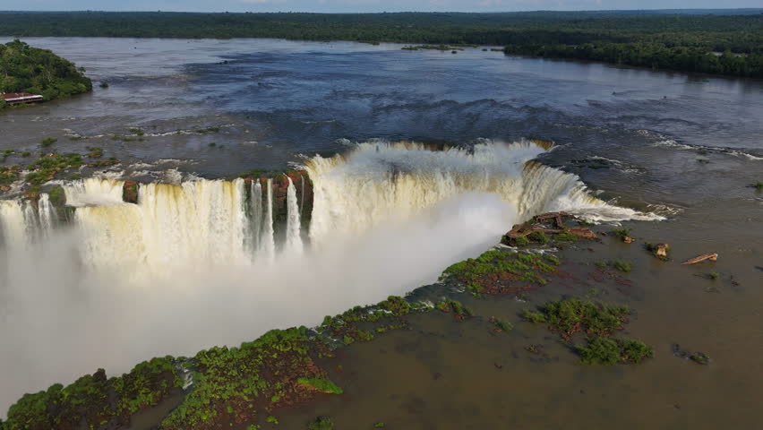 Video flies over Iguazu Falls in Brazil. Water drops into the canyon as mist fills the air. The jungle spreads along the horizon and every frame shows the force and beauty of nature