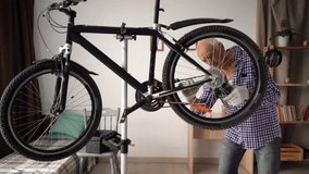 Elder man repairing bicycle and fixing drivetrain on wheel in home workshop. chain repair, mechanical work, personal project, and indoor maintenance of transport equipment. - Powered by Shutterstock - Get 15% off with code: PIKWIZARD15