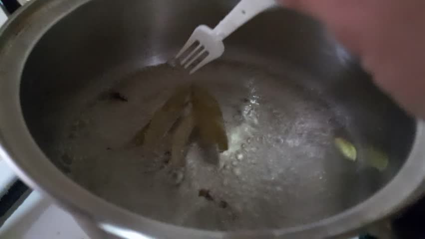 Water heating with cinnamon, cardamom, and bay leaf in a heater for healthy nutritional tea. Making tea with spices. Medicinal spice tea.