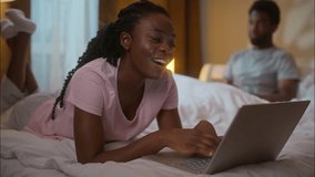 Happy African family couple wife relax using laptop husband mobile phone bedroom night ethnic married spouses gadget addiction funny resting browsing app computer chatting smartphone at home evening - Powered by Shutterstock - Get 15% off with code: PIKWIZARD15