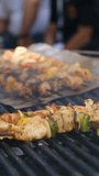Vertical video of a grill master cooking shashlik with pieces of meat vegetables and spices over open flames outdoors. Street meat food with great taste and aroma. Hot delicious grilled meat. - Powered by Shutterstock - Get 15% off with code: PIKWIZARD15