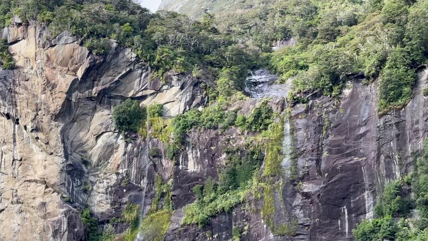  Picturesque view of the waterfall from the water. Cruise on a boat in Milford Sound, New Zealand.