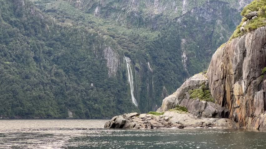  Picturesque view of the waterfall from the water. Cruise on a boat in Milford Sound, New Zealand.