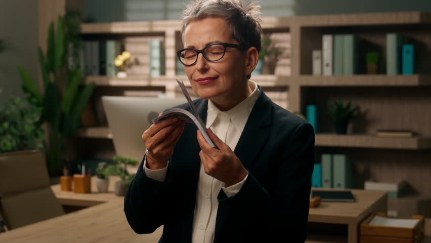 Portrait happy smiling funny Caucasian business woman old businesswoman senior mature female retired employer in office sniffing smell money aroma sniff smelling cash finance dollars looking at camera