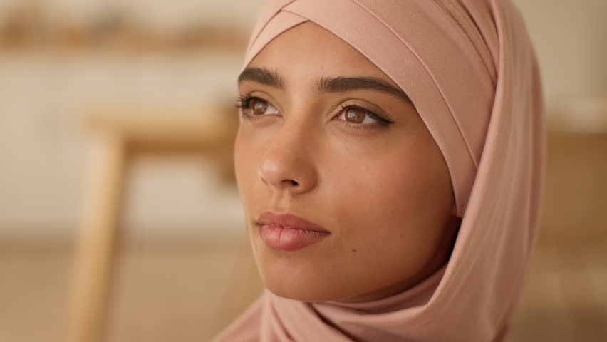 Close up serious pensive thinking solution contemplate dreaming religion eastern portrait female face Islamic woman Muslim girl ethnic Islam Arabian lady wearing pink hijab looking away think indoors