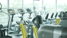Modern gym interior with cardio equipment including treadmills, elliptical trainers, and exercise bikes in a bright, spacious fitness studio with large windows. - Powered by Shutterstock - Get 15% off with code: PIKWIZARD15