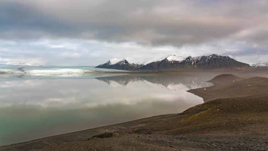 Glacial Lake Landscape with Mountain Reflections and Cloudy Sky