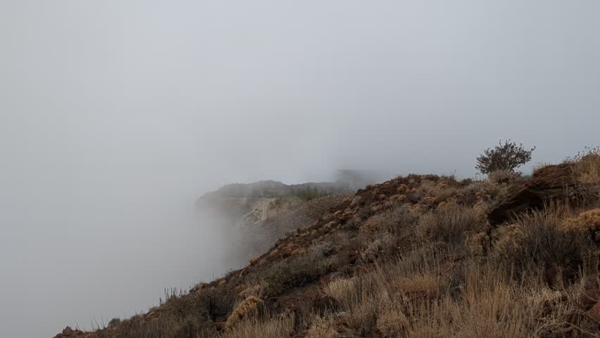 Tenerife dramatic panoramic scene of hills with strong winds blowing clouds across the rugged mountain landscape during a hiking trip.Canary islands Spain
