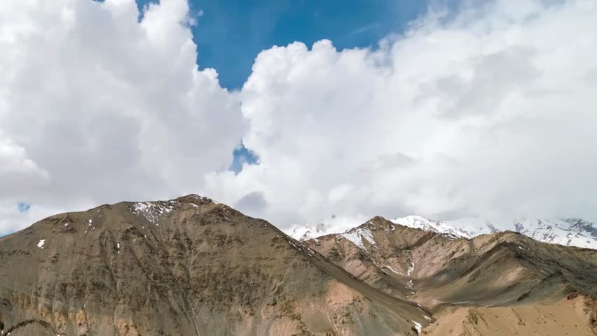 Majestic Mountain Range with Snow-Capped Peaks and Fluffy Clouds