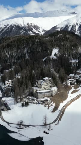Drone panoramic view. Winter  of St. Moritz in Switzerland with snow-covered buildings and alpine landscape. Hotel WaldHaus am See in the background.