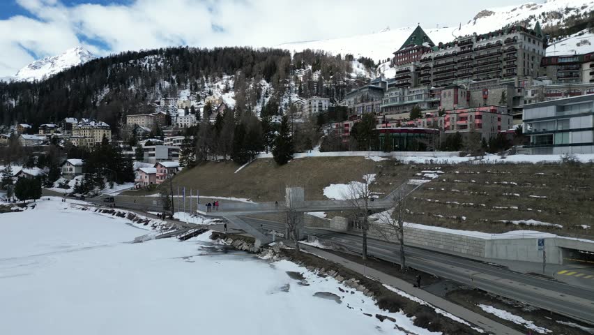 Winter  of St. Moritz in Switzerland with snow-covered buildings and alpine landscape. Park with frozen lake and City view. Drone panoramic view. 
