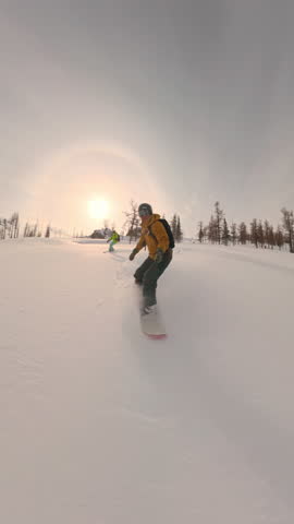 Snowboarders drops into white slope between pine trees on cold sunny day. Snow flies underboard in expression of speed, winter health, action sport and pure alpine outdoor freedom.