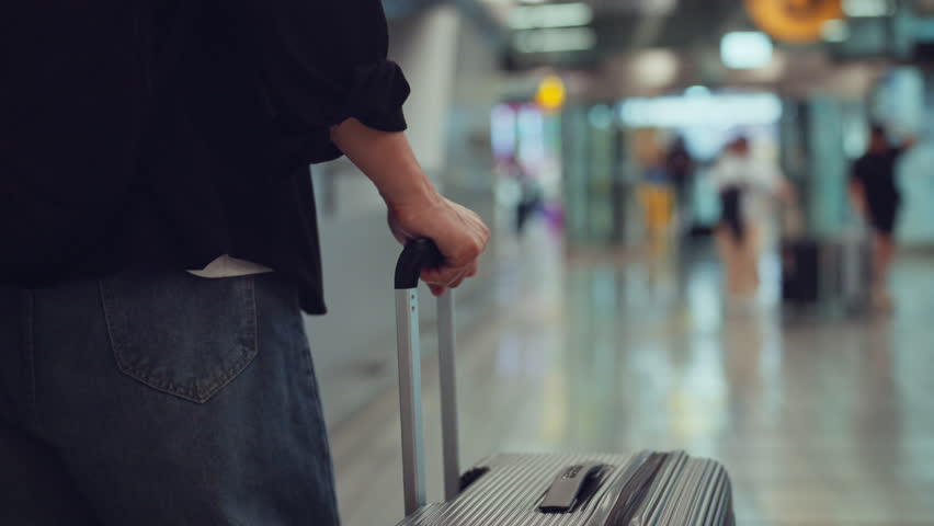 Rear view - Male traveler walking with luggage or suitcase at the modern airport terminal, man on way to flight boarding gate, Ready for travel or vacation journey