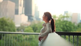 Asian woman wearing headphones standing on bridge in city park during spring evening, looking at urban surrounded by trees – relaxing moment and healthy lifestyle with nature and fresh air - Powered by Shutterstock - Get 15% off with code: PIKWIZARD15