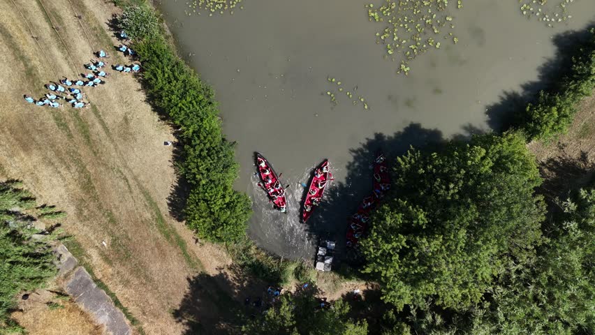 Top-Down Drone View of Red Canoes Paddling Through Lily Pads