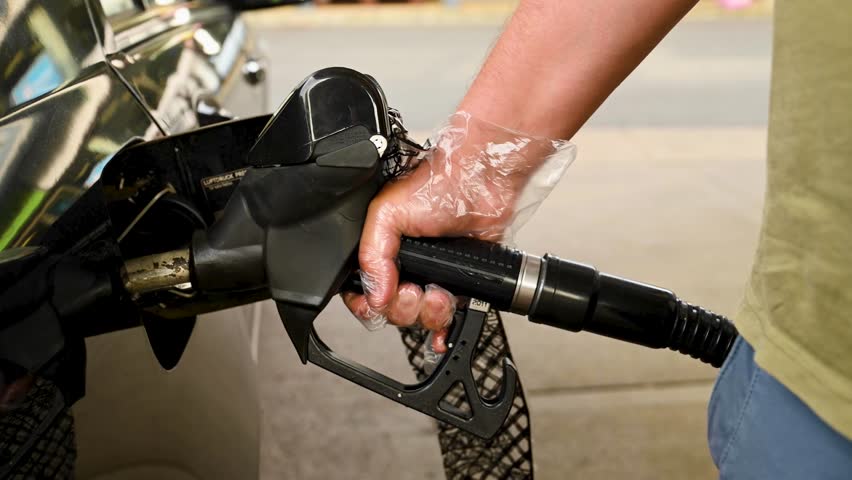 Man driver hand refilling the car with fuel at the gas petrol station. 