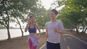 Asian young couple doing running exercise in the morning outdoors garden. Attractive man and woman feel happy and relax, spend their romantic day jogging side by side through a beautiful garden path. - Powered by Shutterstock - Get 15% off with code: PIKWIZARD15