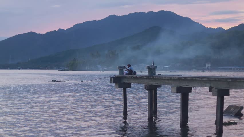 Fisherman Sitting on Pier During Sunset