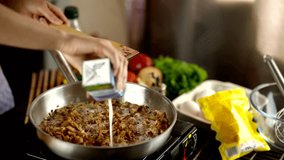 Chef cooking pasta carbonara. hands pouring cream into a frying pan with cooked bacon and onions on a stove. Fresh vegetables and cooking ingredients  a recipe in progress. Traditional pasta carbonara - Powered by Shutterstock - Get 15% off with code: PIKWIZARD15