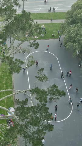 Aerial view of people roller skating at an outdoor rink in a park in Golden Gate Park, San Francisco, California, USA. People are enjoying recreational activities on a sunny day.