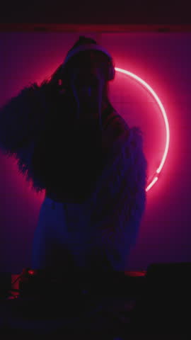 Woman listening techno music party, female make dj set, fur coat in night club. Red neon circle