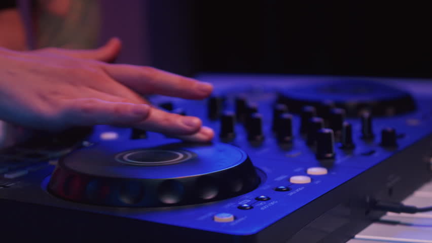 Close up: hand of DJ uses a mixer to mix the music. The artist's fingers bring the tracks together at a party. The art of electronic music in nightclubs. Mixer sound console board machine.