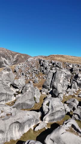 Close vertical drone flyover of rocky outcrops at Castle Hill under bright midday light, dolly passing hikers below
